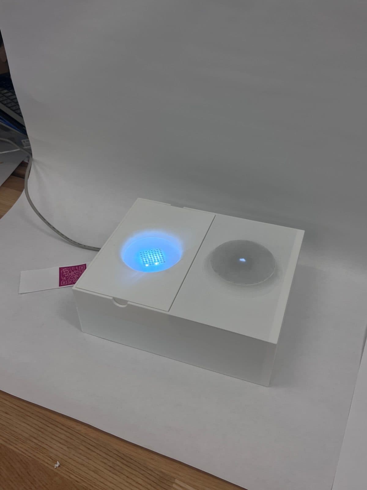 The first version: a flat white box with two wells, an LED matrix lit under one and a frosted dome over the other.