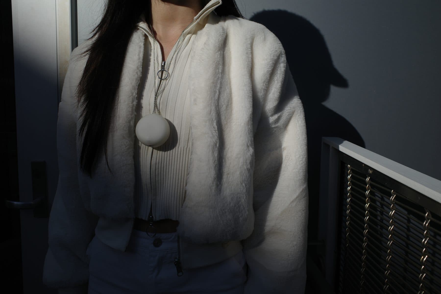 Pebbi worn as a pendant over a white jacket