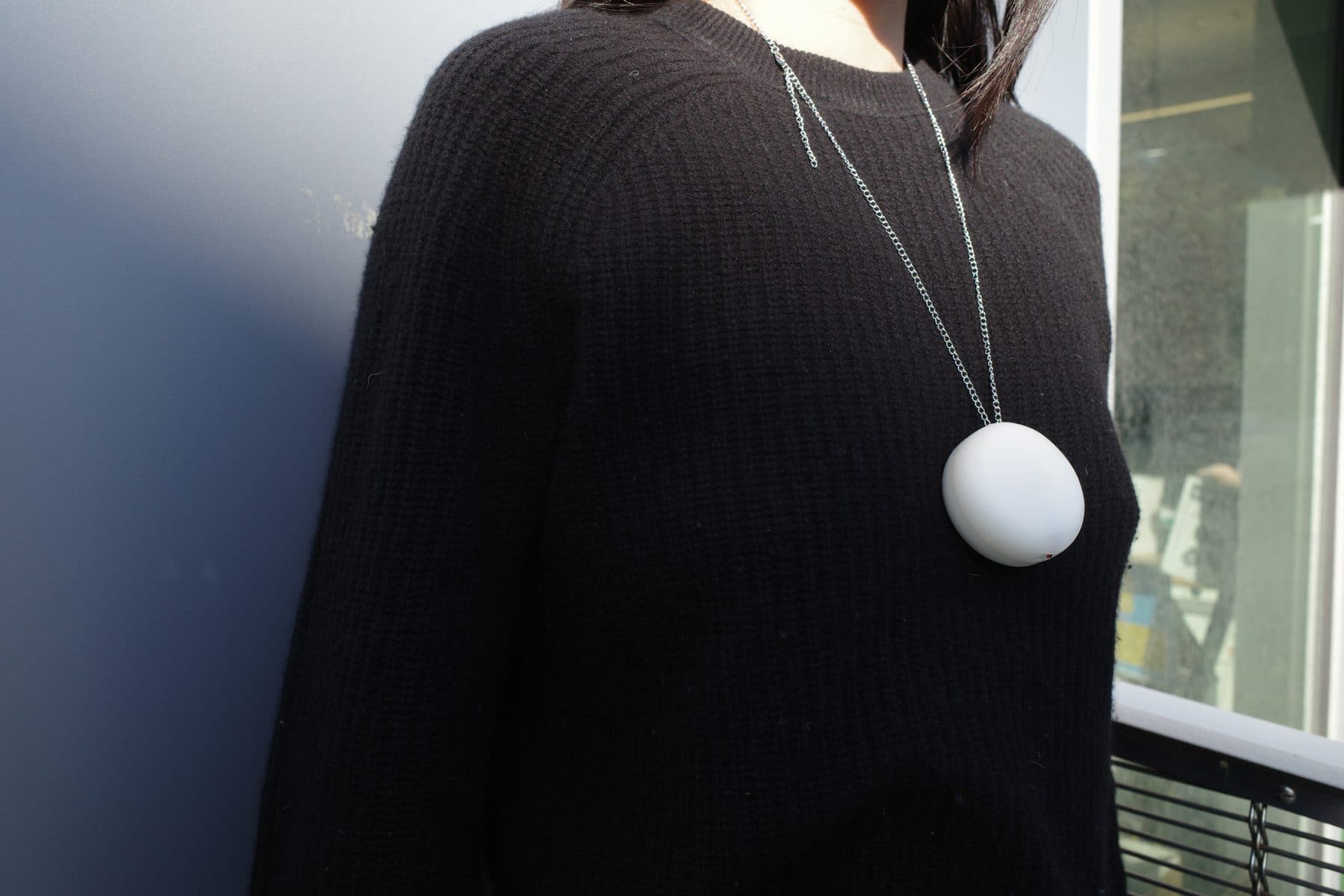 Pebbi worn as a pendant over a black sweater